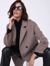 Tapado clásico color visón, con solapas de muesca, doble botonadura y bolsillos de parche.