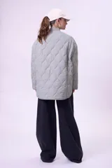 Campera acolchada color gris claro, con cuello mao y cierre frontal con botones a presión. Tiene bolsillos laterales y corte holgado.