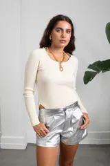 Polera de morley color manteca, con cuello redondo, manga larga y diseño ajustado al cuerpo con aberturas laterales en el ruedo.