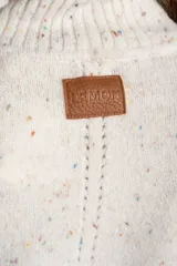 Polera de punto con diseño oversize, cuello alto y mangas largas con paneles laterales en contraste. Presenta un tejido jaspeado con motas multicolores y detalles de lurex.