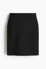 Pollera tubo a la rodilla de tiro alto en punto grueso color negro, con bolsillos al bies, trabillas para cinturón y cierre oculto en la parte trasera.