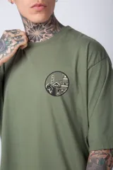 Remera de corte oversize color terracota, con cuello redondo y manga corta. Presenta un estampado circular pequeño en el pecho con motivos orientales.