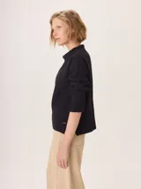 Buzo de lana color beige claro, con cuello chimenea y manga larga. Presenta trenzas de punto grueso en el frente y en los puños, con un diseño texturizado que se asemeja a espigas o ramas.