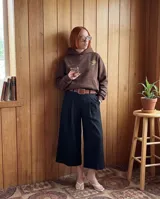 Canguro oversize color marrón con capucha y bolsillo frontal. Presenta un estampado gráfico circular en la espalda con tipografía estilizada en color crema.