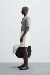 Bermuda de algodón color beige claro, de corte regular fit, con cintura elástica ajustable mediante cordón. Presenta bolsillos laterales y un bolsillo trasero de vivo.