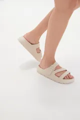 Sandalias de goma color negro con diseño de tres tiras cruzadas y hebilla lateral ajustable.