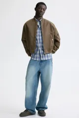 Campera bomber de nylon levemente acolchada, con cuello, puños y bajo acanalados. Presenta cierre frontal, bolsillos laterales con botón a presión y un bolsillo con cierre en la manga.