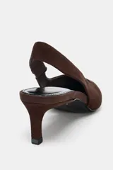 Zapato destalonado de ante color marrón, con tacón kitten fino y punta afilada. Cuenta con una tira trasera elástica para mayor ajuste.