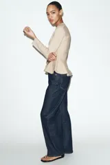 Chaqueta entallada de punto con escote en pico y manga larga. Presenta un diseño con bajo en evasé tipo peplum y cierre frontal con botones forrados a tono.