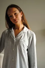 Camisa celeste con cuello clásico, cierre frontal con botones, manga larga con puños abotonados y bolsillo de parche en el pecho.