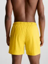 Short de baño amarillo de largo medio, con cintura elástica, cordón ajustable y hebilla con logo. Incluye bolsillos laterales y bolsillo trasero con cremallera.