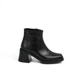 Bota corta de cuero negro con plataforma y taco cuadrado. Presenta un diseño de textura acanalada en la parte posterior del talón y cierre lateral.