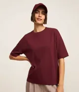 Blusa básica de mujer color negro, confeccionada en malla encorpada de algodón, con cuello redondo y mangas cortas de corte oversized con sisas desplazadas.