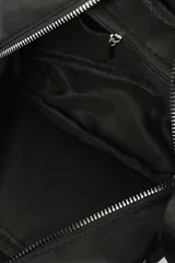 Bandolera color beige con correa ajustable negra. Cuenta con un compartimento principal con cierre y un bolsillo frontal con cierre.