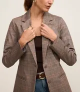 Blazer marrón con estampado de cuadros, confeccionado en punto roma. Tiene solapa en el cuello, cierre con un botón, bolsillos delanteros y corte entallado.