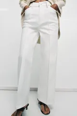 Jeans blancos de tiro alto con diseño wide leg, detalle de nervio delantero y pespuntes marcados a contraste. Presenta cierre frontal con cremallera y botón, y cinco bolsillos.