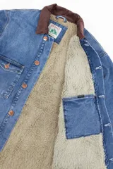 Campera de jean azul con cuello de corderito marrón, cierre con botones metálicos, cuatro bolsillos frontales y puños con botón.