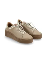 Sneaker Adelaida de suela elevada, confeccionado en cuero vacuno prémium en color beige con detalles blancos en el talón, cordones blancos y suela de plataforma color marrón.