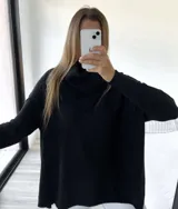 Polerón negro de corte oversize con cuello caído y mangas largas con puños acanalados.