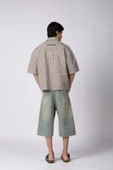 Camisa de manga corta de popelina con patrón a cuadros, calce boxy y largo a la cintura, con bolsillos y canesú cortados en diagonal.