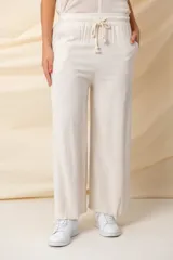 Pantalón ancho color beige, de hilo, con cintura elastizada ajustable con cordón y bolsillos laterales.