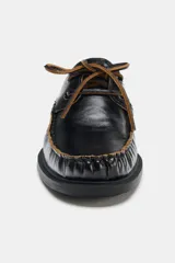Zapato tipo náutico de piel color negro, con detalle de pespuntes en contraste, cordones decorativos y puntera redonda con costura fruncida.