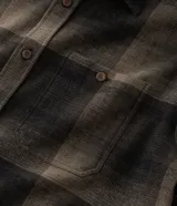 Camisa de franela a cuadros en tonos de azul marino y gris oscuro, con corte regular, manga larga, cuello camisero, cierre frontal de botones y un bolsillo en el pecho.