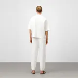 Polo de mujer color crudo, confeccionado en punto cerrojillo. Presenta cuello con solapa y escote en pico, y mangas cortas.