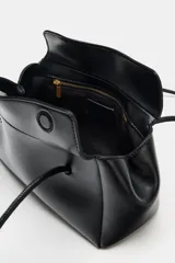 Bolso de hombro negro de formato alargado en símil cuero, con doble asa fina, cierre imantado y bolsillo interior con cremallera.