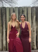 Vestido largo sin mangas con escote en V halter y aberturas laterales (cut-outs) en la cintura. El cuerpo superior presenta un llamativo diseño estampado multicolor, mientras que la falda larga es de tejido texturizado brillante en color verde esmeralda con inserciones godet en el ruedo.