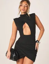 Vestido mini ajustado de color negro, con cuello alto, hombros estructurados, sin mangas y abertura frontal tipo cut out. Presenta un diseño drapeado en la falda con corte cruzado.