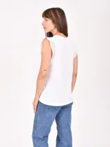 Remera blanca sin mangas con detalle de encaje en los hombros, cuello redondo y corte recto.