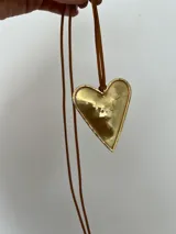 Collar con tres dijes de corazón irregular hechos a mano en alpaca o bronce, con tiento de gamuza negro y cuentas plateadas. El largo del tiento permite darle varias vueltas o usarlo largo.
