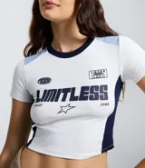 Remera de corte ajustado estilo college, confeccionada en algodón con elastano. Presenta cuello redondo, mangas cortas con recortes en color celeste y laterales en azul marino. Incluye estampado frontal con la palabra 'LIMITLESS' y detalles gráficos.
