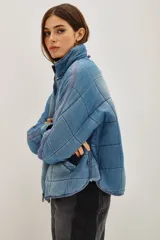 Campera acolchada de corte holgado con diseño de costuras cuadradas, cierre frontal con cremallera y cuello alto. Presenta un acabado lavado en tonos gris y negro.