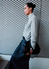 Pollera midi de corte recto y tiro alto, confeccionada en tejido estructurado de color gris oscuro. Presenta un diseño minimalista con costuras verticales que estilizan la silueta.