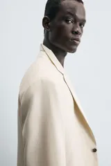 Blazer de corte regular fit confeccionado en tejido con lana. Presenta cuello con solapas de muesca, cierre frontal de un botón, bolsillos de vivo en el pecho y en la cadera, y aberturas en la espalda.