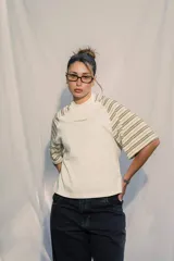 Remera unisex de jersey color blanco con mangas raglán a rayas horizontales en tonos verde oliva y blanco. Presenta un pequeño bordado en el pecho.