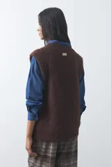 Chaleco de punto con textura afelpada, cuello redondo y hombros marcados. Presenta una silueta relajada y un diseño sin mangas.