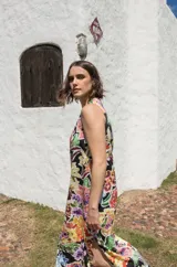 Vestido midi sin mangas con corte recto y tajos laterales en el ruedo. Presenta un estampado floral multicolor sobre base negra y cierre con botón en la espalda.