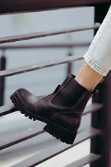 Bota tipo chelsea de cuero color marrón oscuro, con paneles laterales elásticos y suela track robusta con plataforma.