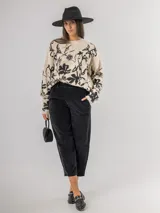 Sweater de punto con calce oversized, fondo color crudo y diseño estampado de flores en color negro. Presenta cuello redondo y mangas largas.