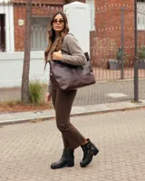 Botas de cuero estilo biker en color marrón oscuro con efecto desgastado. Presentan un diseño de caña corta con correas ajustables con hebillas metálicas y detalles de remaches. Cuentan con una suela de goma dentada y tacón bajo.