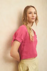 Top corto color blanco roto, con escote cuadrado, manga corta abullonada con lazos ajustables en el borde y textura arrugada en el tejido.