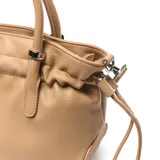 Cartera chica color camel, confeccionada en símil cuero con textura granulada. Cuenta con asas de mano fijas, correa larga de tela ajustable y desmontable, y detalles de cordones ajustables en los laterales. Incluye herrajes metálicos plateados y logo de la marca en la parte frontal.