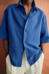 Camisa marrón de corte boxy fit, con tejido estructurado, cuello bowling, manga corta y un bolsillo aplicado en el pecho. Cuenta con cierre frontal de botones.
