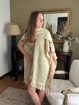 Ruana tejida en telar, hecha en pura lana de oveja Merino fino. Diseño en color natural, guardas texturadas y terminación con flecos.