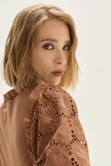 Blusa blanca de algodón con mangas abullonadas de broderie con diseño floreado. Presenta volados en el cuello y hombros, con un estilo romántico y femenino.