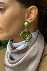 Caravanas de clip con diseño de flores abstractas en color verde seco. Presentan una esfera superior lisa y una esfera central texturizada, conectadas a pétalos de resina con movimiento fluido.