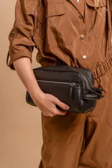 Neceser rectangular de símil cuero color beige claro, con dos compartimentos principales con cierre y un bolsillo frontal con cierre. Posee un asa lateral para transporte.